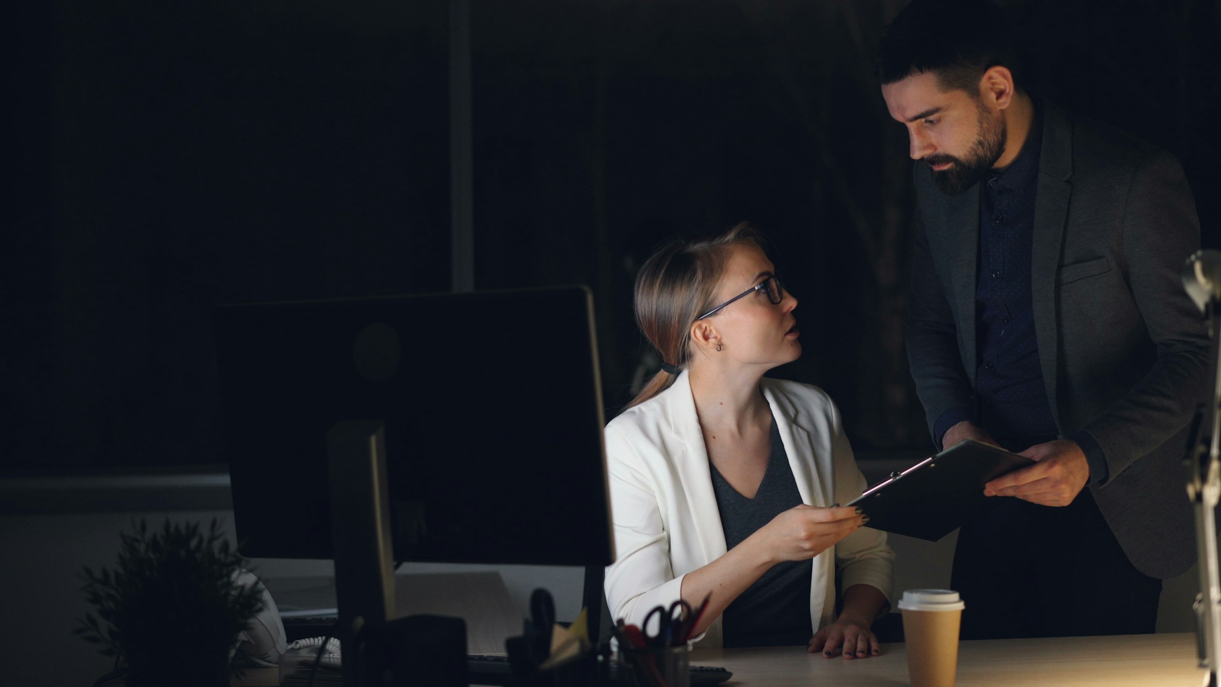 Two colleagues reviewing a document late in an office